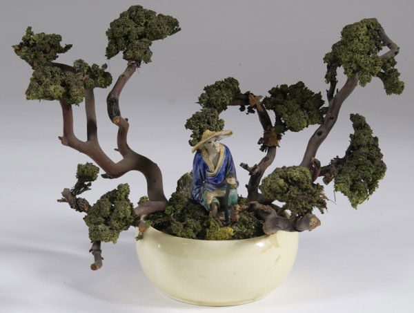 Mudman Figure Sitting under Moss Tree: Mudman figure sitting with his legs crossed, dressed in a blue robe and holding a staff. Seated in a yellow planter with moss tree. 11" H; excellent condition.