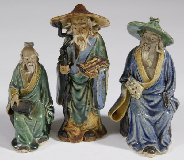 3 Late 19th/Early 20th C. Mudmen Figures: To include an old man figure holding a staff and a scroll in a green robe, 6" H; impressed CHINA, hat has been repaired. An elderly man sitting, holding a scroll wearing a blue robe and green hat; 5.2
