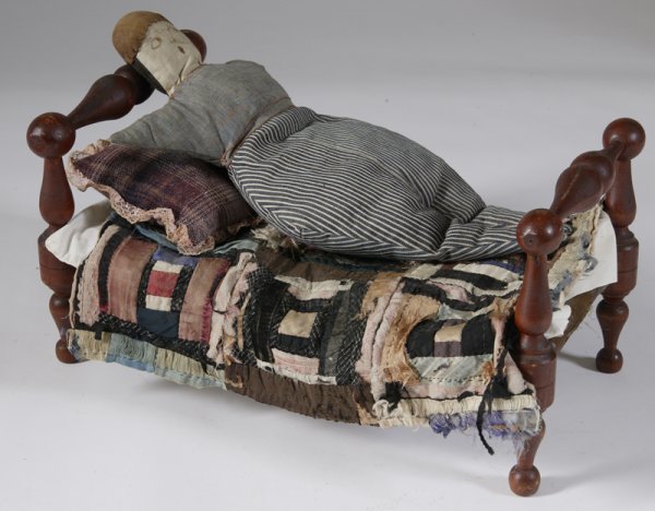 Very Fine 19th C. Doll Bed and Cloth Doll: Bed is in the Empire taste with bold turnings and original surface, with rope holding the mattress. Decorated with lace pillow and makeshift quilt. 8.5" H x 16.25" L x 9" W. Doll with striped trousers