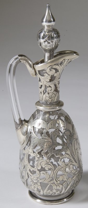 Fine Gorham Glass and Silver Overlay Cruet: Floral decorated silver overlay with central cartouche monogrammed. Stopper with double tear finale. 9" H. Glass broken 1/2" x 1/4" with other stress cracks toward middle, otherwise a very fine piece