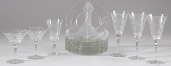 18 Pieces of Clear Etched Glass Tableware: Includes 12 plates with leaf, floral and stem designs, 8" Dia. A single wine glass with leaf and circle designs, 6.25" H. Two martini style glasses with etchings that match the plates, 5" H, and three