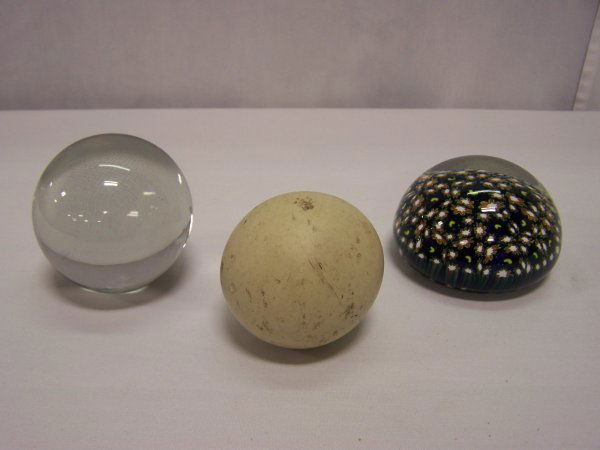 Lot Of Paperweights And Stone Ball: Two glass paperweights one clear and one cobalt with floral design along with a light clay colored stone ball. Good condition.