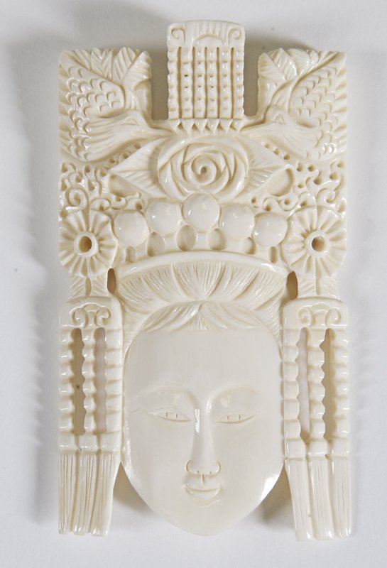 Chinese Carved Ivory Goddess Face: Smiling face of a goddess wearing headdress decorated in ornate floral and bird decorations with three hanging tassels to either side. 3.5" L, and comes with small stand for display. Excellent conditi