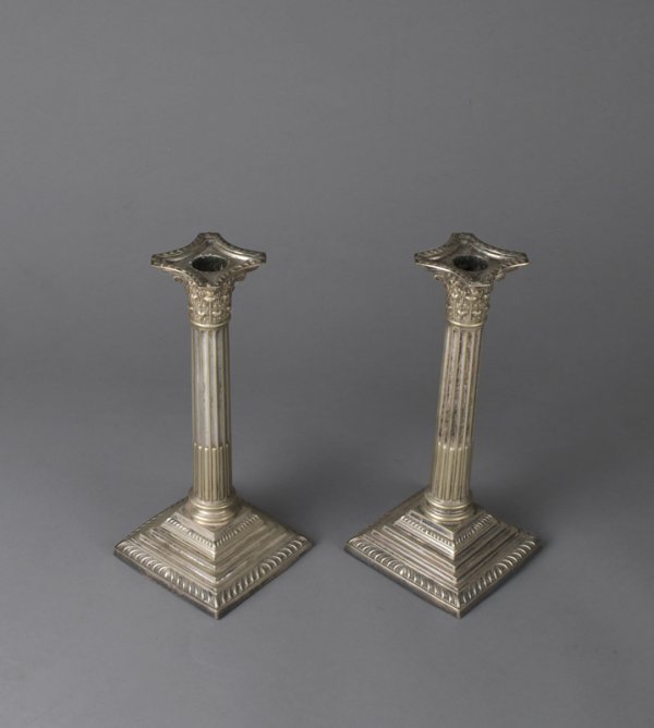 Fine Pair of Antique Edwardian Candlesticks: Silverplated column candlesticks with Corinthian capitals and graduated step base. Base is weighted. Measure 9.5" high. Loss to silverplate on both candle holders.