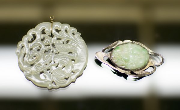( 2 ) Chinese Qing Jade Plaques: ( 1 ) carved to depict an octopus chasing a fish, with gold wire mount, 2.125"D, the second in apple green jade carved to depict peaches, now mounted in a silver victorian mount.1.25" Both 19th C or e