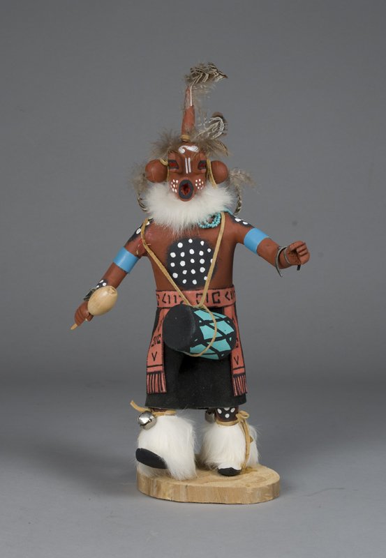 Very Fine Mud Head Kachina Doll: Painted in red, with circular black and white dotted medallions on arms, chest and back. Red and black leather skirt with geometric designs on sash. Fur neckline, head ornaments and boots, holding a r