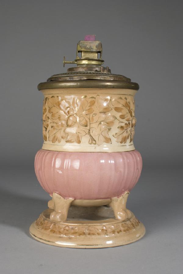 Antique Avalon Faience Majolica Oil Lamp Base: Avalon Faience oil lamp established in Baltimore in 1897. Footed base with attached underplate, decorated in raised leaves and ribbed pink center. Includes oil font by Badger. 8.75" H (base only), cra