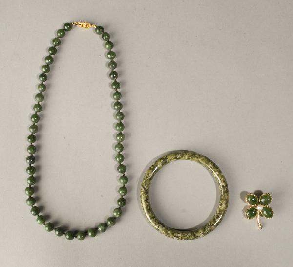 (3) Piece Chinese Carved Jade Jewelry: Includes a dark green jade beaded necklace with uniform beads, 17" L. A jade and pearl pin in metal mount to depict a four leaf clover, 1.5" L. And a spinach jade bangle bracelet, 3" Dia. 19th/20th Ce