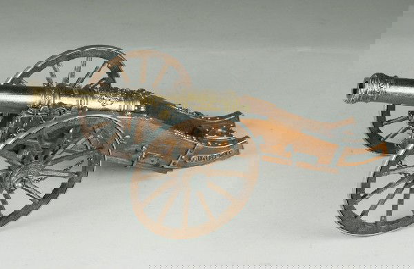 Miniature Collectible Cannon: Louis XIV replica cannon. Gun carriage and rotating metal rimmed wheels are made of wood. The ornate cannon barrel can be elevated and it has a brass patina. Detachable ram and laddle. 17" L, laddle l