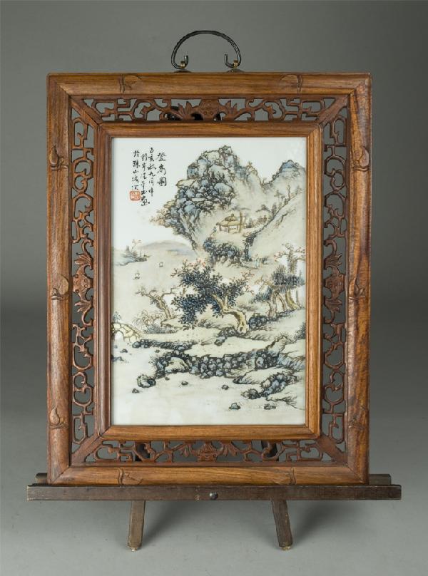 Chinese Painted Porcelain Table Screen: Painted to depict mountain landscape with trees, rocks, home and water with boats. Housed in a carved wood frame with scrolling and four bats on each side. 20.25" H x 15.75" W, (entire). Seal mark and