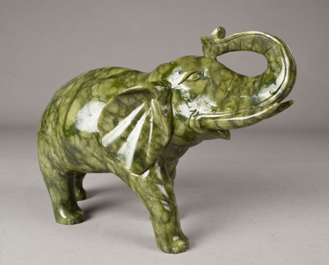 A Massive Chinese Carved Jade Elephant: Finley carved with tusks, and trunk raised, the stone a light emeralds with magnificent deep green veining throughout. 11.5"L x 8.5"H, purchased in California in the 1990's for 5,000.00, small chip to