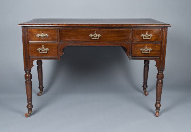 A Fine Small Scale English Desk, Circa 1850: With five drawers, the center drawer with lift top writing slope with tooled leather edge. All drawers with hand cut dovetails. Leather top, original castors, the lock marked Lever 2 on all drawers. 4