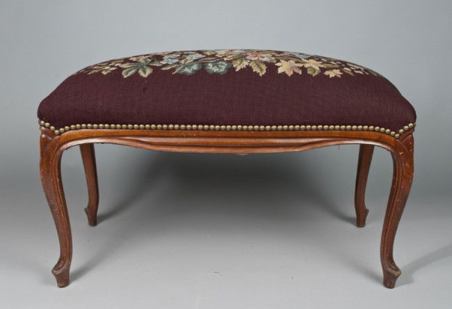 A Fine 19th Century Needlepoint Bench: On four legs with beautiful needlepoint in burgundy with multi-colored floral swag, and brass tacks. 19" H x 30" L x 14.5" D. Nicks and abrasions to wood, some losses and pulls to needlepoint.