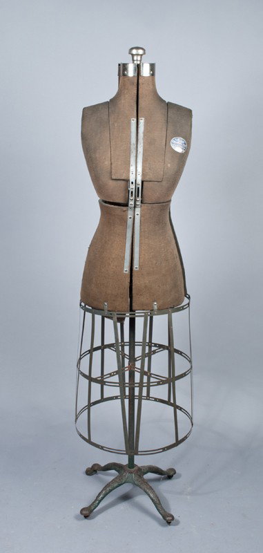 Acme Collapsible Dress Form on Cast Iron Base: With original cast iron stand with four wood posters, the cloth dress form with wire work open bottom, measures 62"H, Circa 1920.