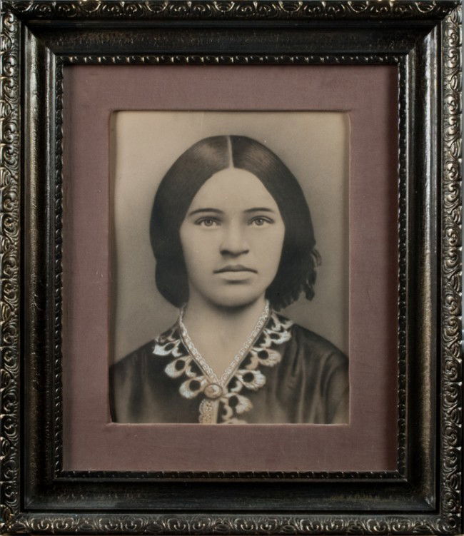 Antique Photograph Of A Native American Girl: With china white embellishments in dress and eyes, large photo measuring 13"H x 9.5"W, sight, velour matt, nicely framed with carved details, circa 1920's.