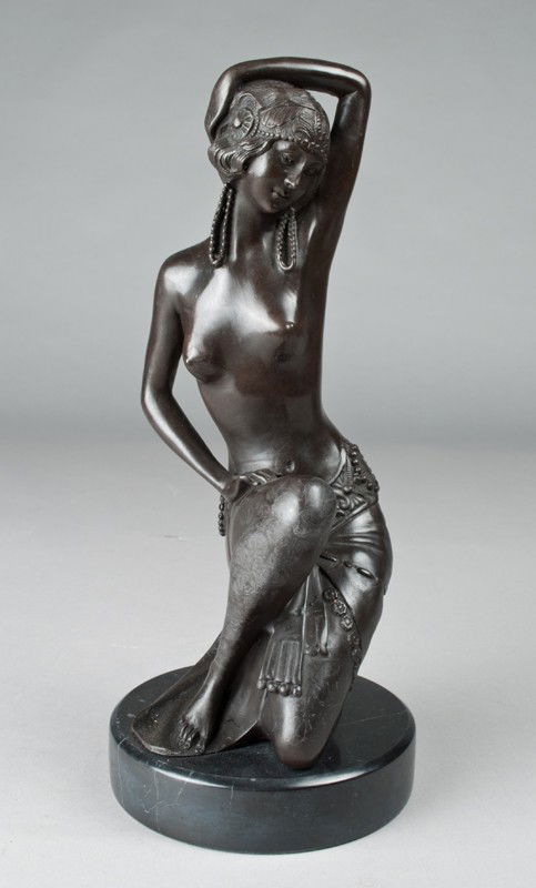 After Demetre Chiparus Art Deco Dancer Bronze: Bronze depicting a half nude female art deco dancer kneeling and with hand over her head, attached to marble base. 12.75" H x 6" W, signed in back.