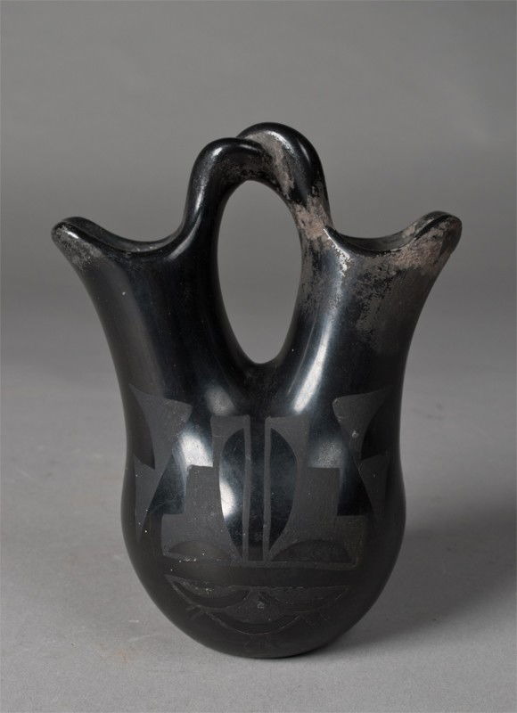 A San Ildefonso Blackware Wedding Vase: Attributed to Maria Martinez, circa 1925. 6" H, circa 1920's-1930's. Losses under both spouts and under part of handle, small stress crack to bottom.