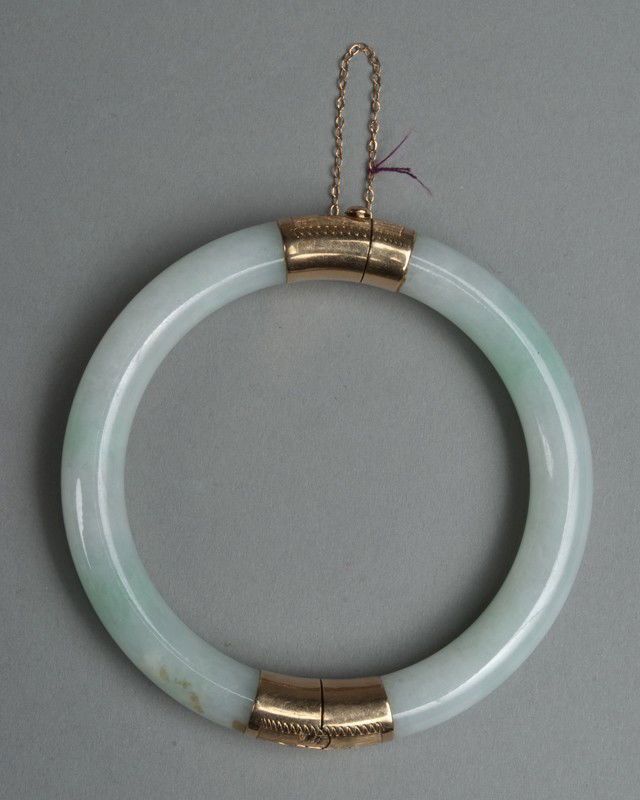 Chinese Jadeite And 14K Gold Mounted Bangle: A fine light apple green hinged bangle with 14K gold mounts, the stone with touches of lavender, 3"diameter, circa late 19th - early 20th century.