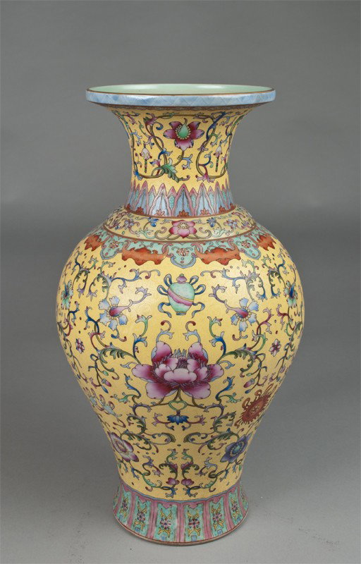 A Fine Chinese Famille Rose Porcelain Vase: Of baluster shape, finely enameled with lotus and climbing tendrils, the top of neck with hanging bats, the rim decorated in gilt, all against a graviata yellow ground, the base with four character se
