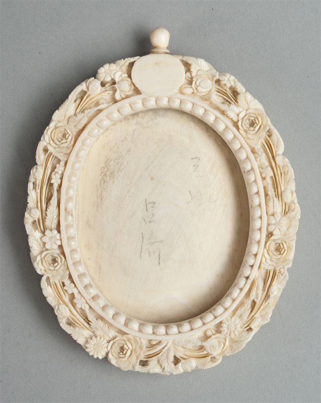 Chinese Carved Ivory Picture Frame: The oval frame Finley carved with flowers and fauna, deeply carved, the sides with carved ribs, the interior boarder with rope design, with ivory back and ring hanger, and brass keepers, 4.125"H, circ
