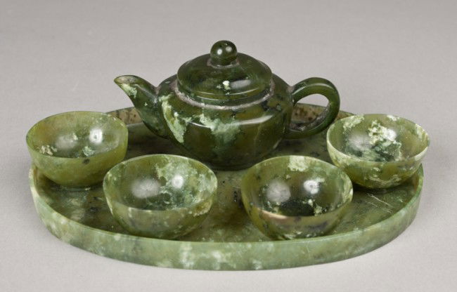 Chinese Carved Spinach Jade Tea Set: The six piece set with four handleless cups, sided oval tray, tea pot and cover, finely polished with no decoration, the stone a spinach green, tray 6.875"L, teapot, 3.875"L, circa 20th century.