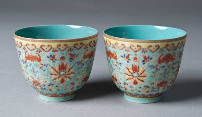 Pr. Of Chinese Famille Rose Porcelain Tea Cups: Footed tea cups in turquoise ground enameled with chrysanthemum's, bats and scrolling designs in iron red, yellow and cobalt, and with gilt rim. Six character mark in iron red on underside. 2 & 5/8" H