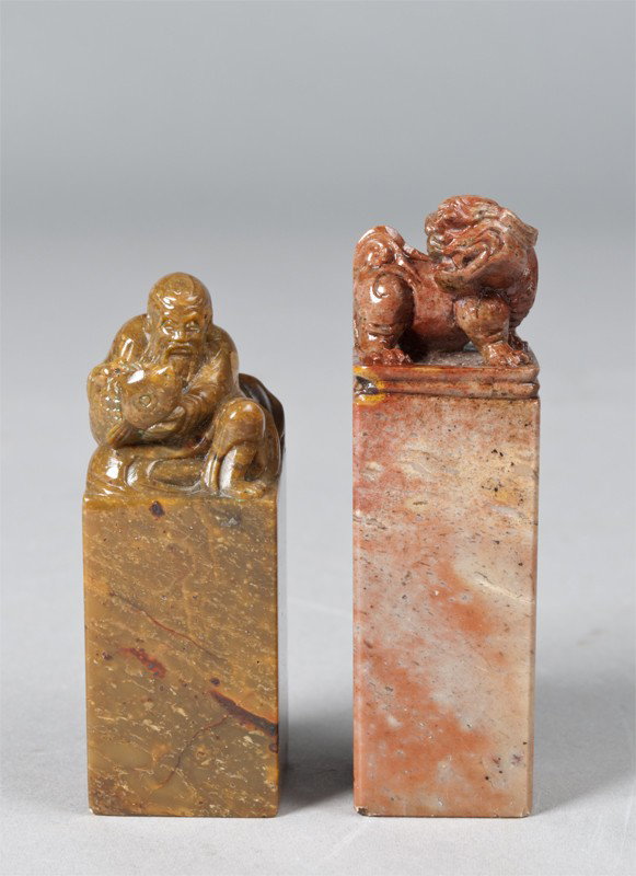 (2) Fine Chinese Soapstone Seals: Each finely carved, one to depict a seated Lohan with carp, the stone a molted caramel color, other with foo dog, the stone a reddish brown. Tallest 2.5" H. Both very fine, private collection Troy, MI