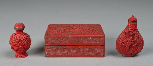 (3) Chinese Cinnabar Articles: Includes a lidded box with peony carvings China in red on underside, a snuff bottle with figural carvings and four character mark on underside in brass, and a smaller composition snuff bottle with lan