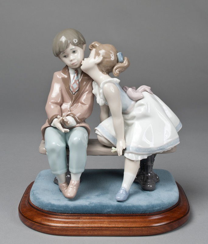 Lladro Porcelain Figurine "Ten and Growing": Finely molded to depict two children sitting on a bench. 7.5" H, includes Lladro custom stand with velour top and original box.