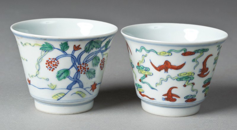 (2) Chinese Du Cai Porcelain Wine Cups: Both finely painted, one depicting trees and fruit and the other depicting bats amid ruyi. Both with six character mark within two circles in underglaze blue on underside. 2.5" H, with custom fitted b