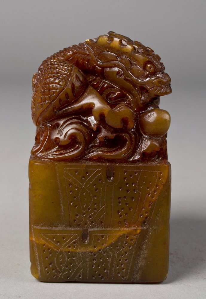 A Fine Chinese Carved Soapstone Seal: The top finely carved to depict a dragon with a flaming pearl, the sides with geometric etchings, and the seal with characters. 4.25" H x 2.25" Sq., chip along base of seal; 1.5". Circa 20th century.