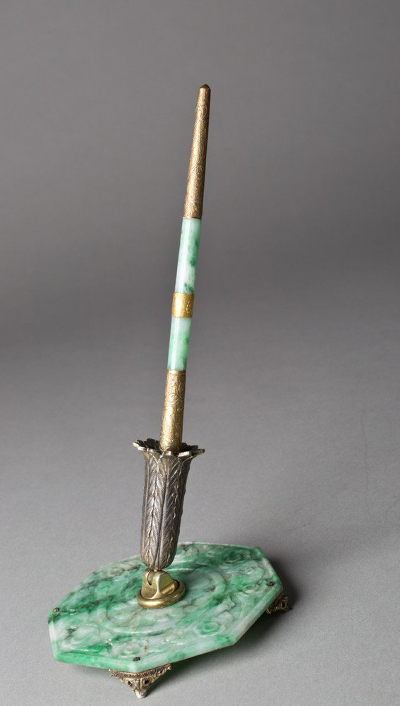Chinese Jadeite and Sterling Pen Holder: The molded apple green octagonal jadeite base with a carved plum blossom motif gilt sliver pen holder and foot base, marked J.E. Caldwell and sterling. 3.5"D and matching pen 19th century.