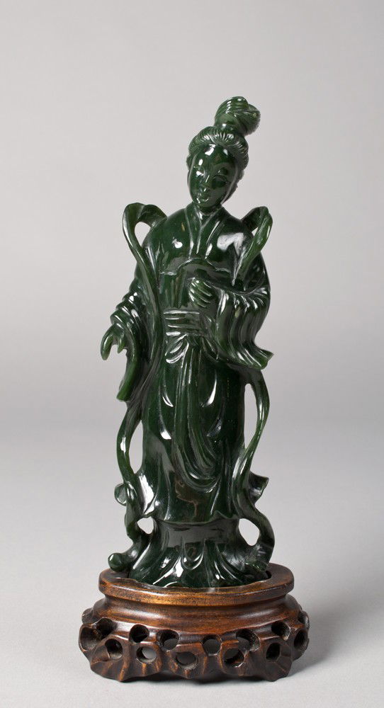Chinese Carved Spinach Jade Guanyin: Finely carved in spinach jade the figure fully robed the stone a deep spinach green with fine polish standing on it's original carved rosewood stand, 7.75"H not including the stand circa late 19th-ear