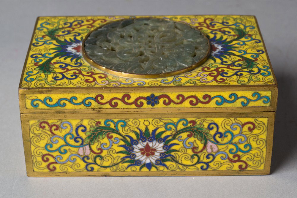 Chinese Gilt Bronze & Cloisonné Inlaid Box: A fine bronze and cloisonné box finely enameled to depict lotus blossoms and tendrils, the top inlaid with a carved circular jade or hardstone plaque to depict bats amongst foliage, 4.375"L X 3.375"D
