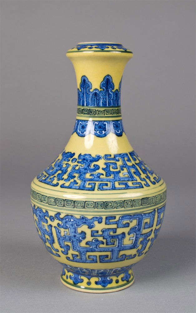 Chinese Tao Tie Porcelain Vase: Yellow ground, decorated in blue symbols with dragons and stiff petals. Six character mark for Great Qing Qianlong Production in underglaze blue on underside. 8.25" H x 4.75" W, circa 20th century.