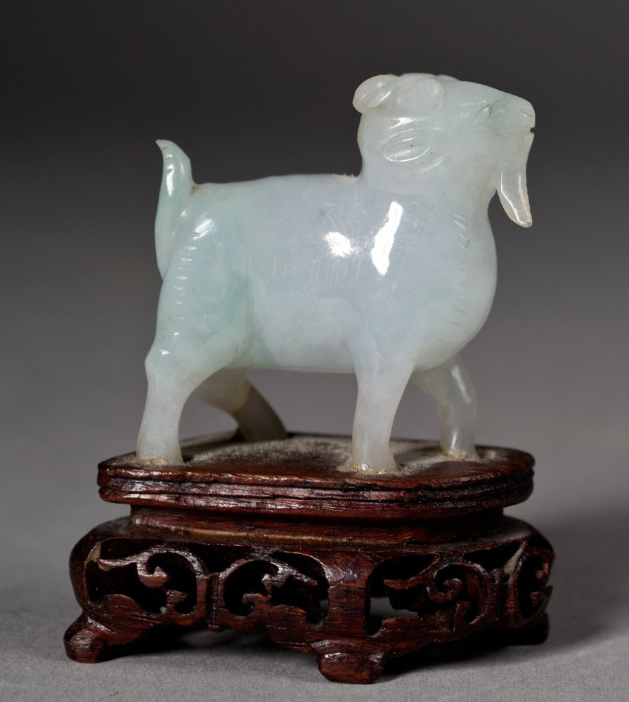 A Fine Chinese Qing Carved Jadeite Goat: Finely carved to depict a standing goat with curled horns and beard, on fitted hardwood stand, 1.5" H x 1.5" W not including the stand circa 19th century.