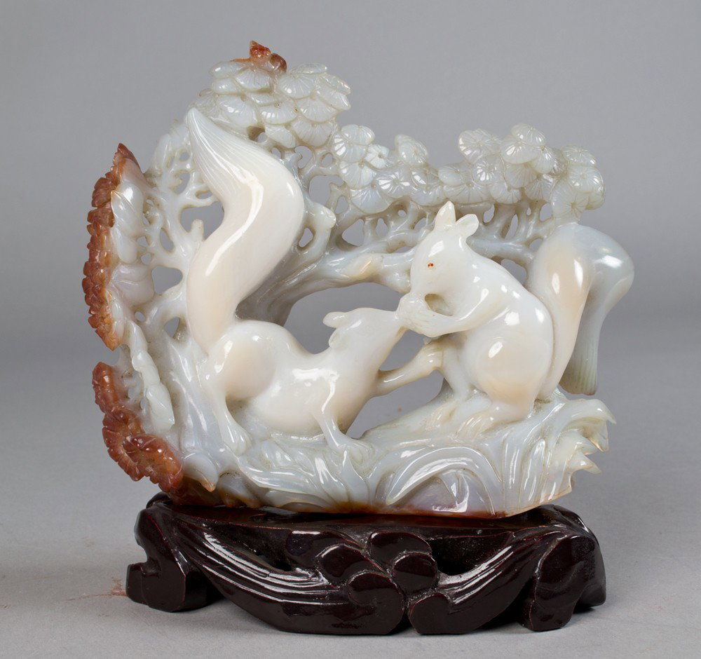 Chinese Carved White Agate Depicting Squirrels: Finely carved to depict two squirrels beneath a pine tree both eating a nut the stone almost a pure white wit russet inclusions along the left side, 6.125"H X 7"W circa early 20th century.