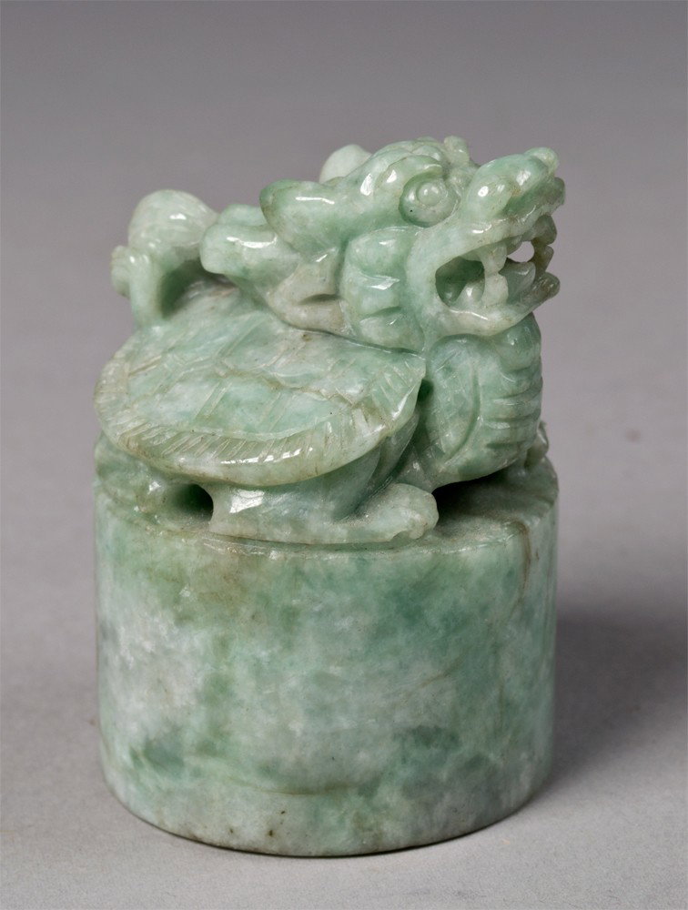 A Fine Chinese Jadeite Seal: Finely carved at top to depict a dragon adorning a turtle shell. 3" H, circa 20th century.