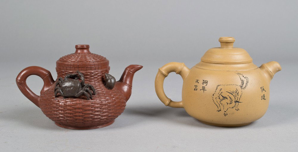 (2) Chinese Yixing Porcelain Tea Pots: To include an example molded to depict basket weave with crab and snail crest seal mark to base and under lid together with a light tan example with etched wolf and calligraphy with seal mark to foot 