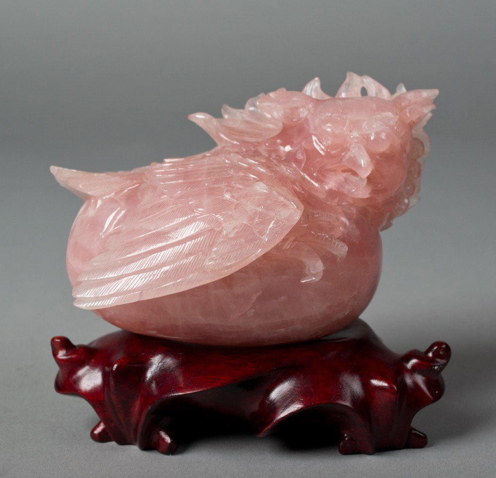 A Chinese Rose Quartz Carving of a Horned Bird: Finely carved to depict a laying bird with horns and ruffled neck feathers on fitted hardwood stand 3.5"H X 4.5"W, not including the stand,very heavy, circa early 20th century.