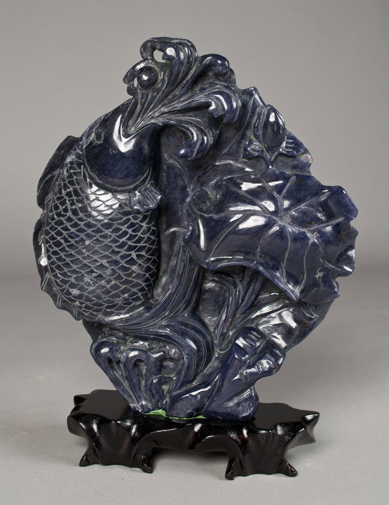 A Very Fine Chinese Sodalite Carving of Carp: Very finely carved to depict a carp shooting water from its' mouth and a lotus pad, with the reverse carved with a large lotus pad. On a custom carved wood stand, and with custom fitted box. 8 & 3/8"