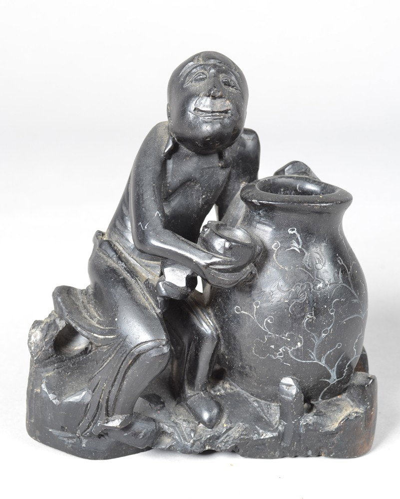 A Fine Chinese Soapstone Carved Vase: Finely carved to depict a seated figure holding a cup on one hand and a large vase in the other. 5.75" H x 5.5" W. Circa early 20th century.