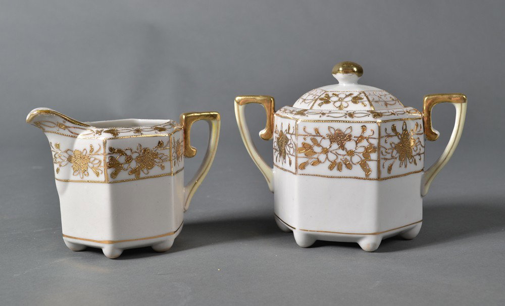 Nippon Creamer and Covered Sugar Bowl: Both white porcelain, decorated with floral panels in gilt, each with yellow painted handles. Marked Hand Painted Nippon transfer. Tallest 4.75" H, circa 20th century.
