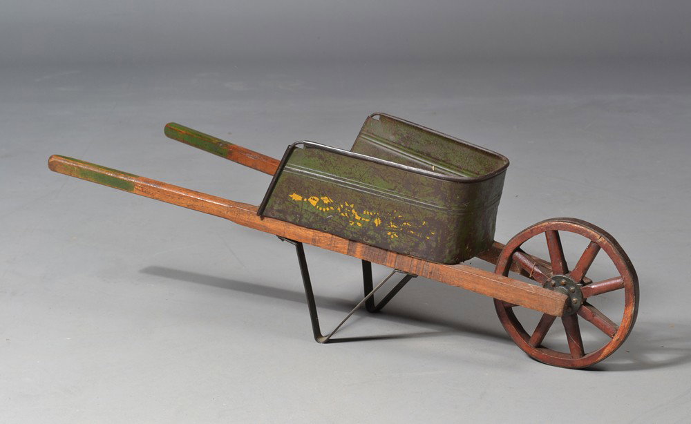 American Child's Wood and Iron Wheelbarrow: With wagon style wheel with iron banding, in original green and red paint and remnants of yellow stencil decoration. Very well made, 33" L. Circa late 19th/early 20th century. Private collection Grego