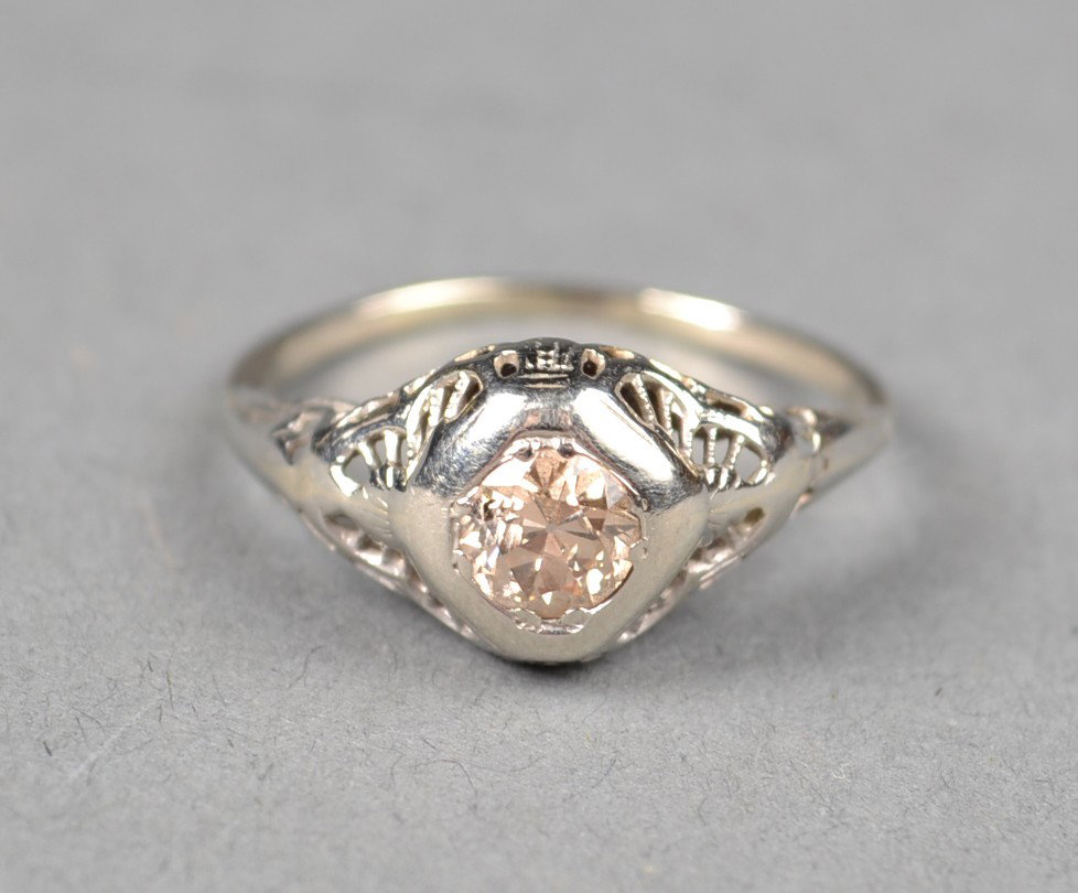 A 14kt White Gold And Colored Diamond Ring: A center colored diamond weighing approximately .50cts, of light brown color, in a 14K white gold filagree mount, tested 14k or better size 7. 3 grams total weight circa 1920's Private collection Clin