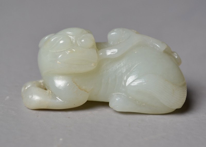 Chinese Qing Carved White Jade Foo Dog: Holding a Lingzi on mouth,with a fine hand polish and exceptional detail, 18th-19th C., 2"L.