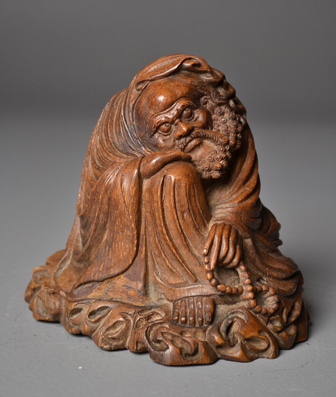 Chinese Carved Bamboo Damo: Seating on ground holding a string of beads, 19th C.