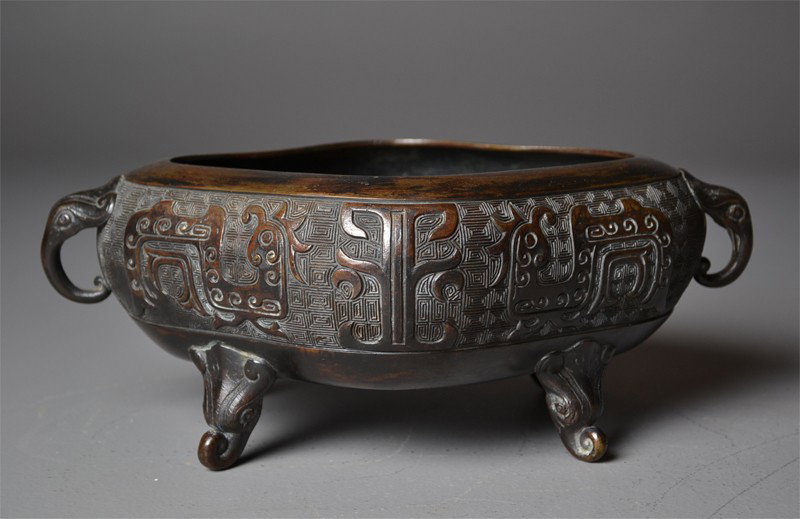 Chinese Qing Bronze Four Foot Censr: Depicting dragons and face of the beast, with four character mark on the base, circa 19th century, 12"H X 8.25"W X 4.5"H.