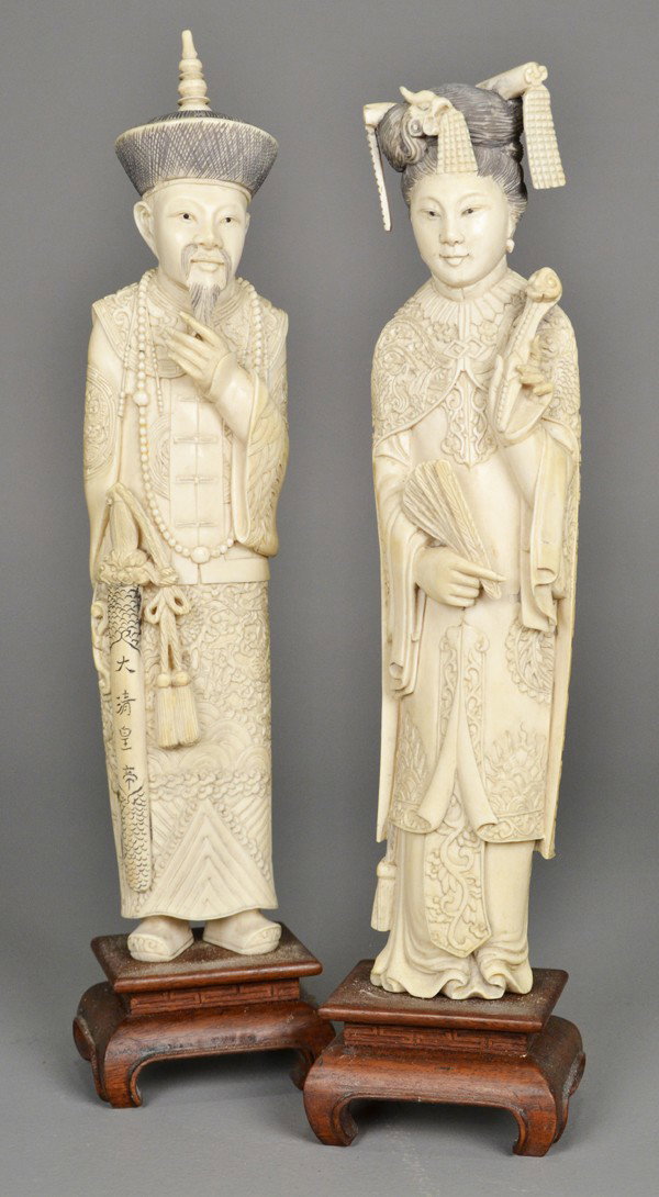Pair Of Chinese Carved Ivory Figures: Both finely carved to depict an emperor and empress, him holding a sword, her with a fan and ruyi scepter, both very well carved, very large measuring 13.5" H not including the finely carved hardwood 