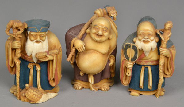(3) Japanese Polychrome Ivory Okimono: Probably Meji period, each finely carved to depict a different Wiseman, each holding a staff, one with bare belly with staff over shoulder, one with hooded robe, and one with scroll in hand and tortoi
